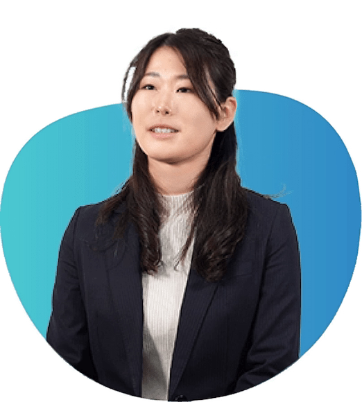 髪をハーフアップにして白いハイネックに黒のジャケットを着て話をしている様子の女性社員の写真