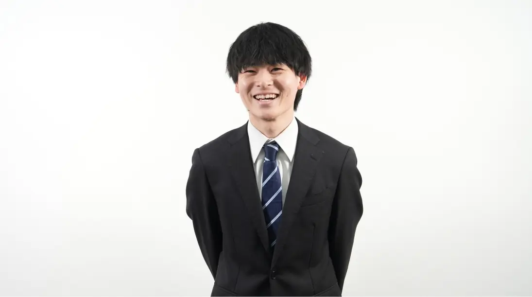 スーツを着た男性社員がカメラに向かって笑顔で微笑んでいる様子