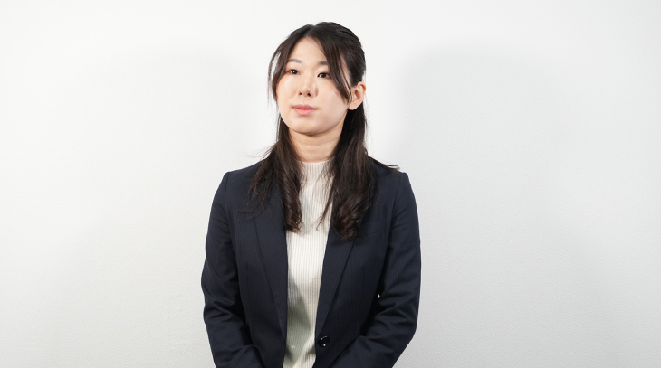 スーツを着た女性社員がカメラに向かって微笑んでいる様子